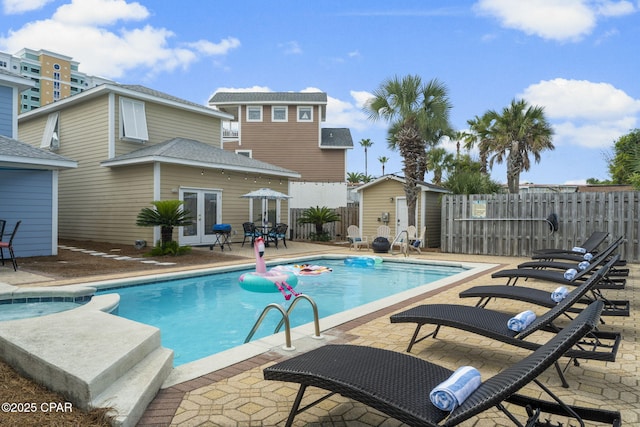 view of swimming pool featuring french doors, a storage unit, and a patio area