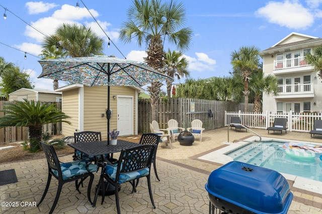 view of patio featuring a fenced in pool, grilling area, and a storage unit