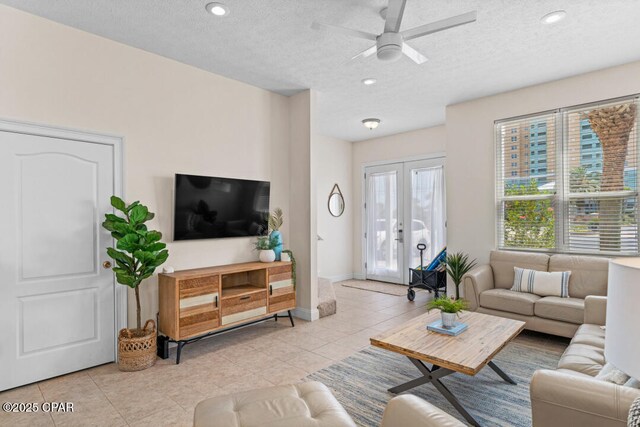 tiled living room with french doors, ceiling fan, and a textured ceiling