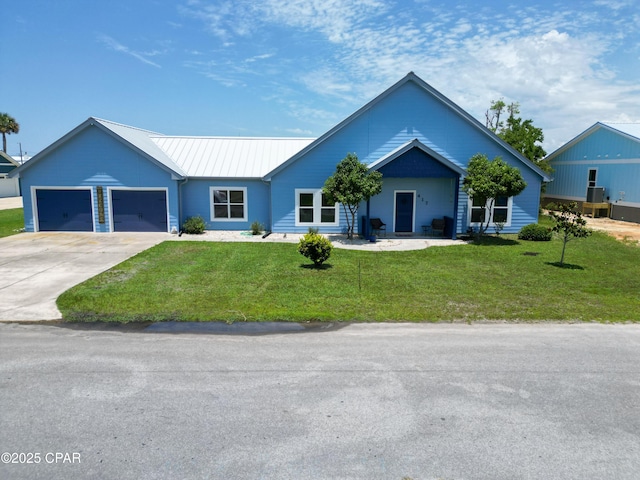 ranch-style home featuring metal roof, a front yard, driveway, and a garage