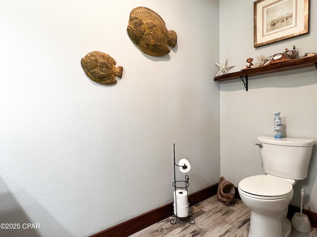 bathroom featuring toilet, wood finished floors, and baseboards