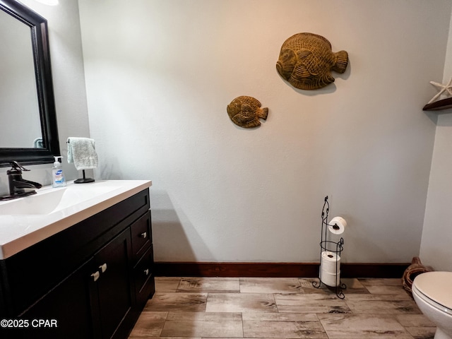 half bathroom featuring toilet, vanity, and baseboards