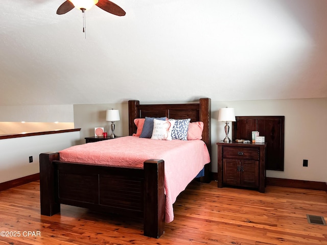 bedroom featuring lofted ceiling, visible vents, hardwood / wood-style flooring, and baseboards