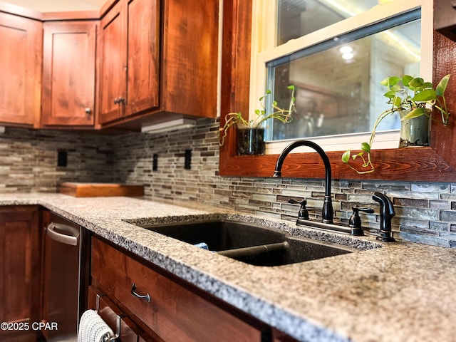 kitchen featuring light stone counters, tasteful backsplash, and a sink