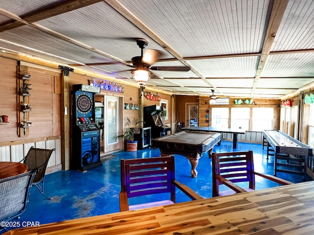 rec room with wooden walls, a ceiling fan, concrete flooring, and pool table