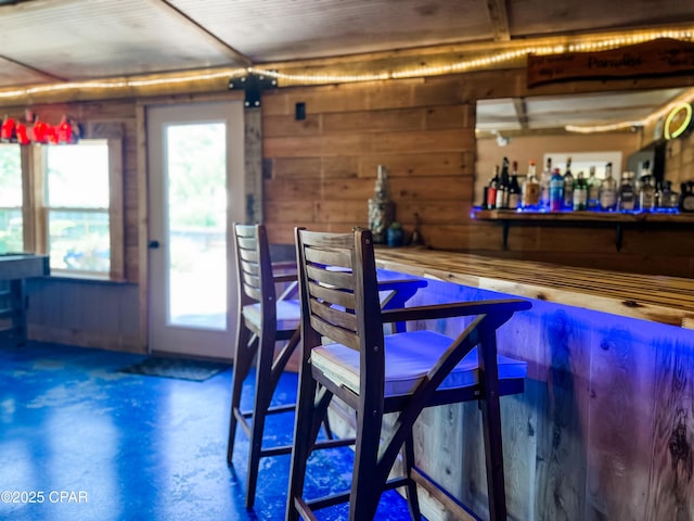 bar featuring wooden walls, a dry bar, and finished concrete floors