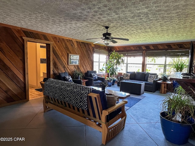 living area featuring wooden walls and ceiling fan