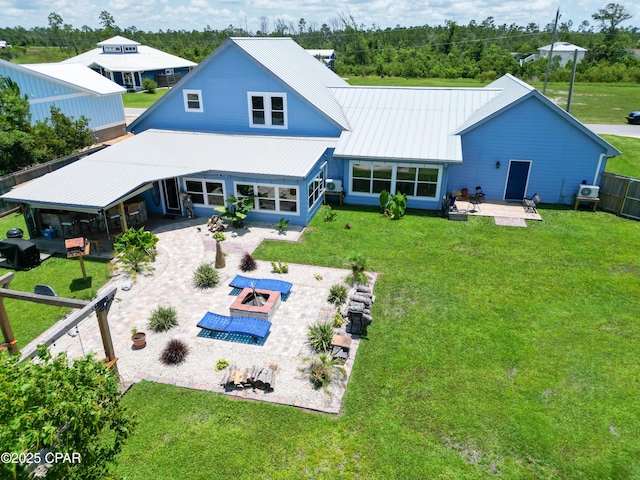 back of property featuring a lawn, a fire pit, metal roof, and a patio