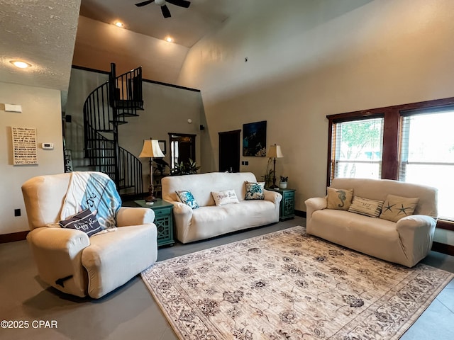 living area featuring a ceiling fan, high vaulted ceiling, stairway, and baseboards