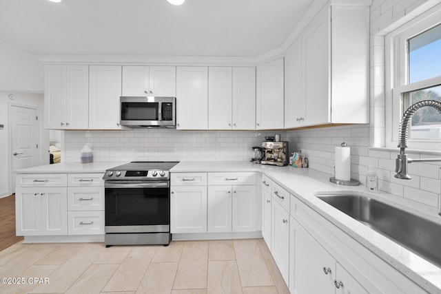 kitchen featuring decorative backsplash, appliances with stainless steel finishes, sink, and white cabinetry