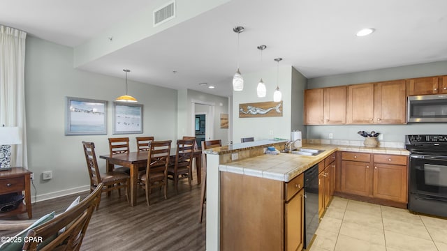 kitchen featuring black appliances, decorative light fixtures, sink, kitchen peninsula, and light tile patterned floors