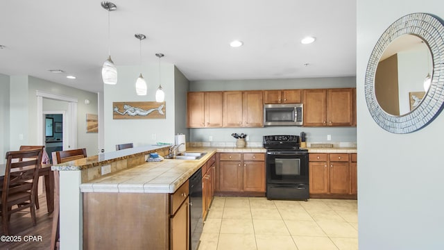 kitchen featuring black appliances, kitchen peninsula, sink, light tile patterned flooring, and hanging light fixtures