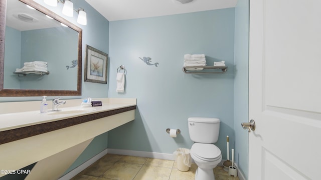 bathroom with toilet, tile patterned flooring, and sink