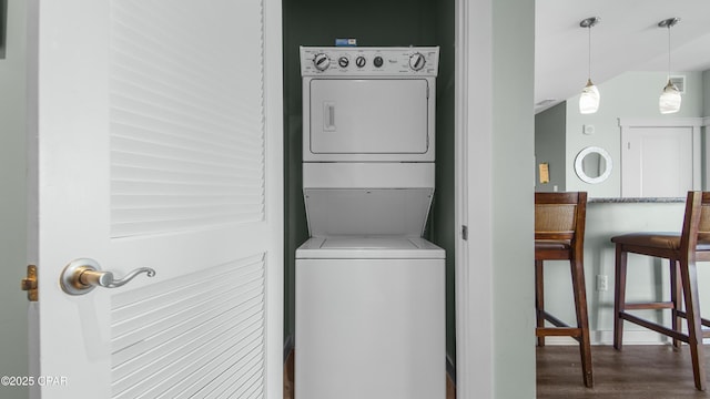 laundry room featuring stacked washer / drying machine and dark hardwood / wood-style floors