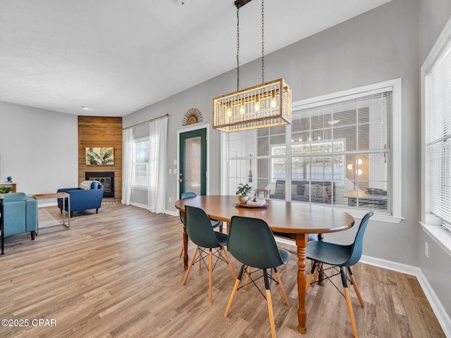 dining space with a brick fireplace, light wood-style flooring, and baseboards