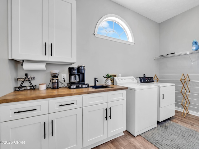 washroom featuring light wood-type flooring, independent washer and dryer, cabinet space, and a sink