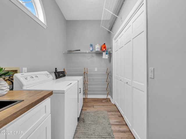 clothes washing area featuring light wood-type flooring, cabinet space, and independent washer and dryer