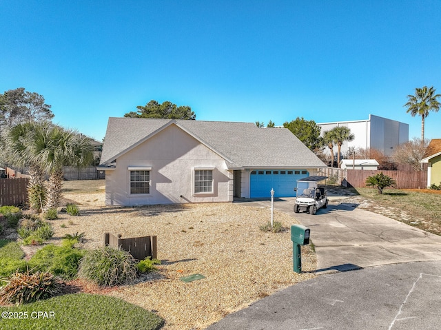 view of front of house with a garage, concrete driveway, roof with shingles, and fence