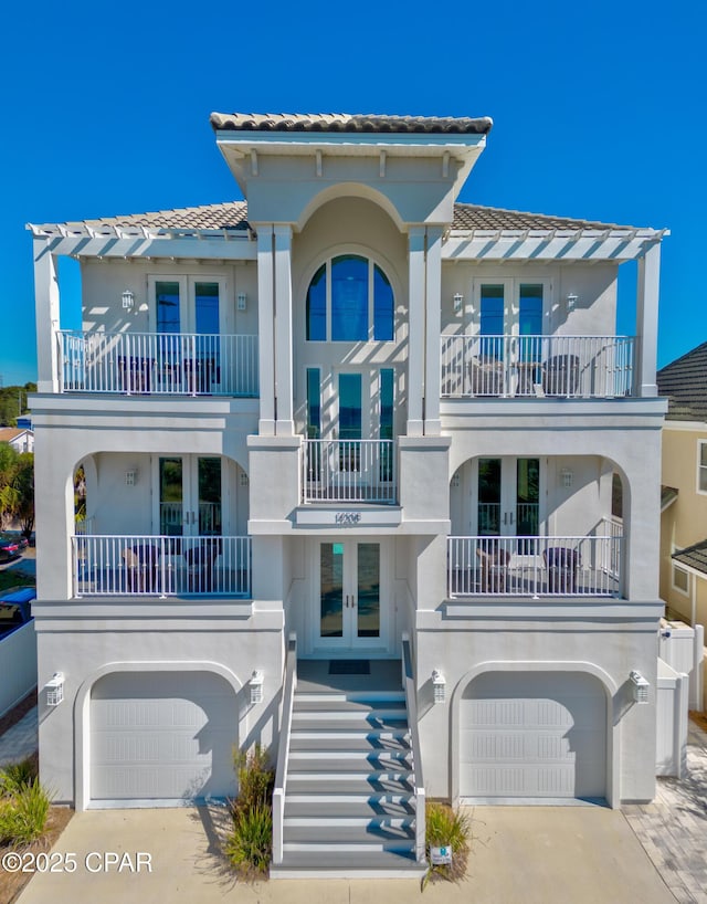 view of front of home featuring french doors, a balcony, and a garage