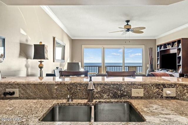 kitchen with stone counters, a sink, a ceiling fan, and crown molding