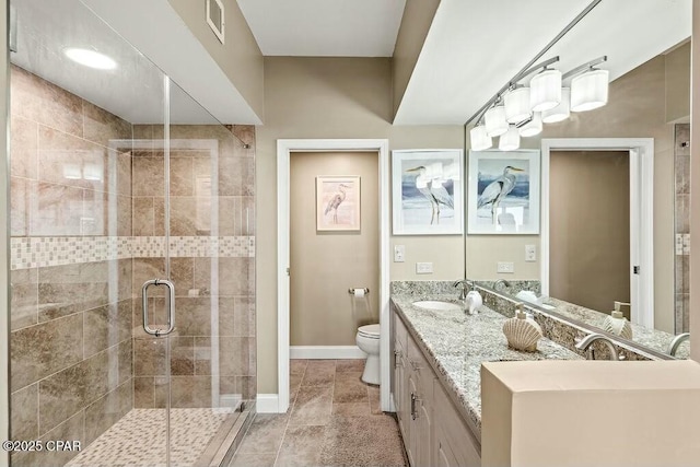 bathroom featuring toilet, a sink, visible vents, baseboards, and a shower stall