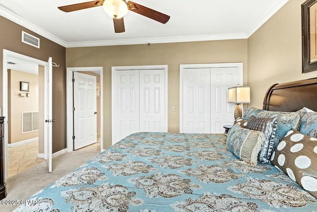 bedroom featuring ornamental molding, visible vents, and two closets