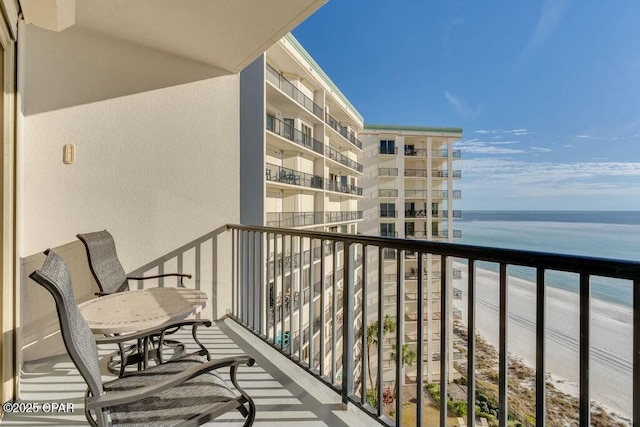 balcony with a water view and a view of the beach