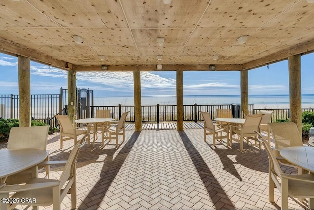 view of patio featuring a water view, fence, and outdoor dining area