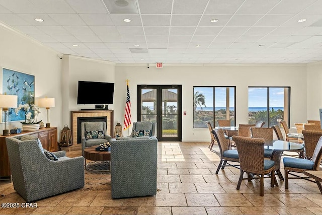 living area with a fireplace with raised hearth, stone tile flooring, french doors, a paneled ceiling, and recessed lighting