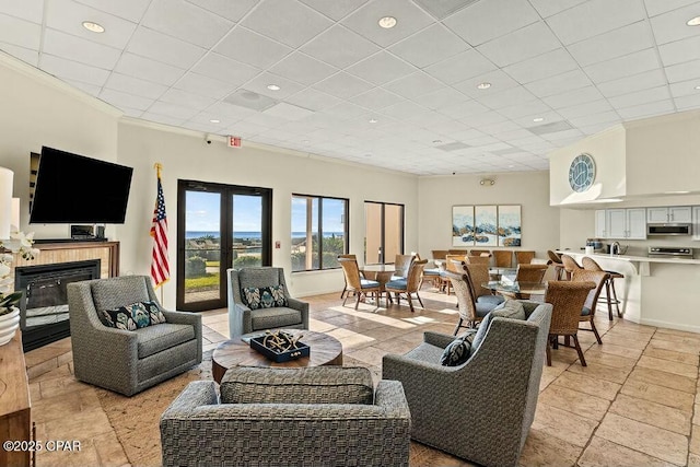 living room with a drop ceiling, a tiled fireplace, recessed lighting, and baseboards