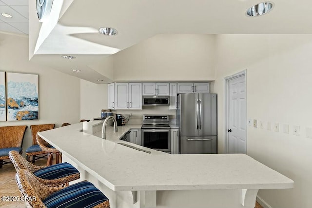 kitchen featuring stainless steel appliances, a sink, a peninsula, and a kitchen breakfast bar