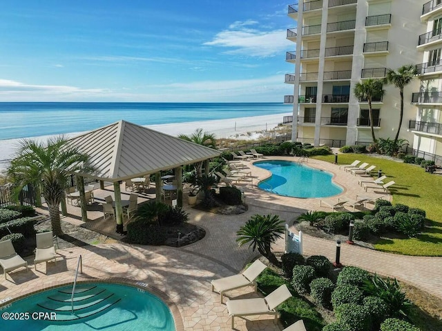 pool featuring a gazebo, a patio area, a beach view, and a water view