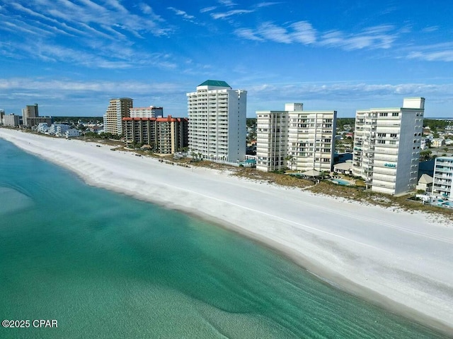 drone / aerial view featuring a view of city, a water view, and a beach view