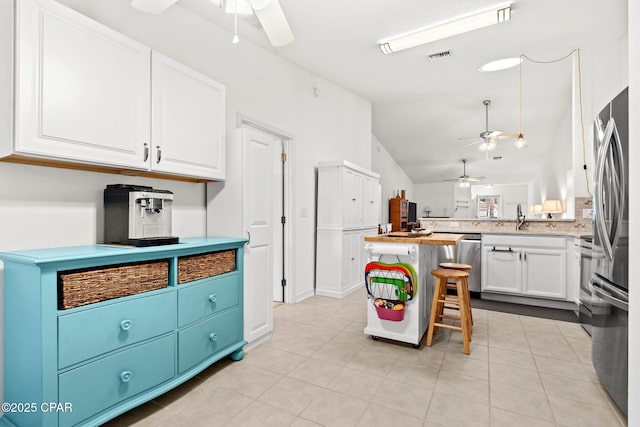 kitchen with white cabinetry, ceiling fan, a kitchen bar, and appliances with stainless steel finishes