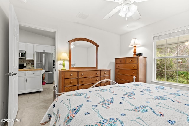 tiled bedroom featuring ceiling fan, lofted ceiling, stainless steel fridge, and ensuite bath