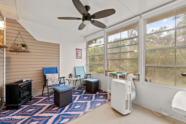 sunroom featuring ceiling fan and a wood stove