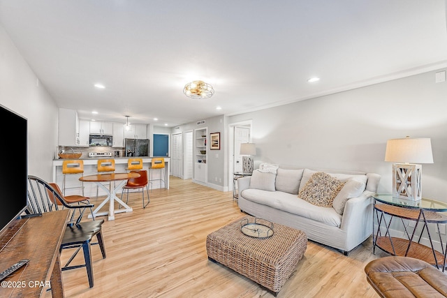 living area with recessed lighting, light wood-style flooring, and baseboards