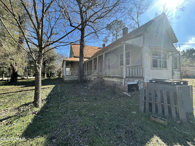 view of side of home with a lawn and covered porch