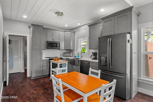 kitchen with decorative backsplash, dark hardwood / wood-style floors, gray cabinetry, and stainless steel appliances