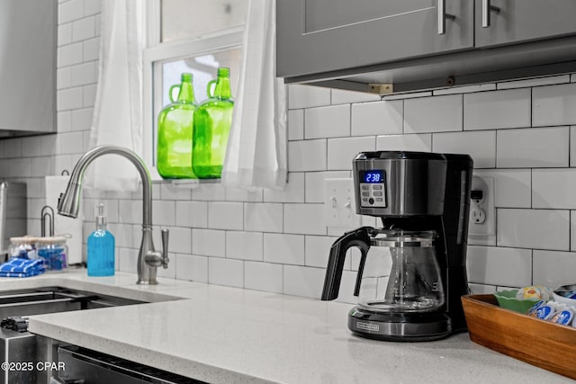 kitchen with light stone countertops, decorative backsplash, and sink