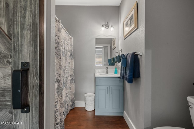 bathroom featuring curtained shower, hardwood / wood-style floors, toilet, and vanity