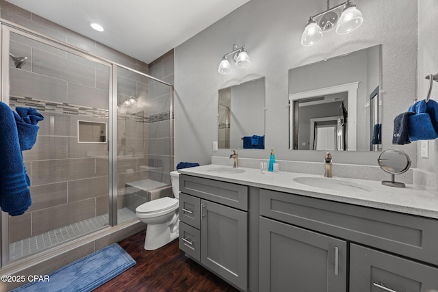 bathroom featuring hardwood / wood-style flooring, toilet, a shower with door, and vanity