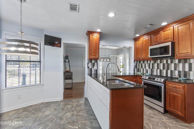 kitchen featuring decorative light fixtures, appliances with stainless steel finishes, sink, and dark stone countertops