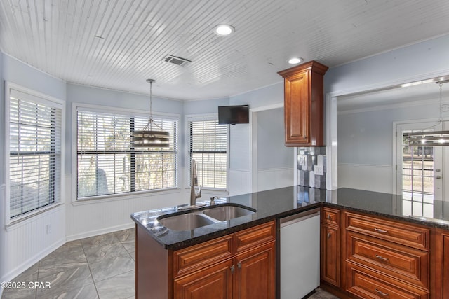 kitchen with kitchen peninsula, dark stone counters, sink, and pendant lighting