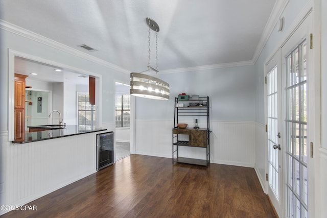 unfurnished dining area featuring sink, dark wood-type flooring, beverage cooler, and crown molding