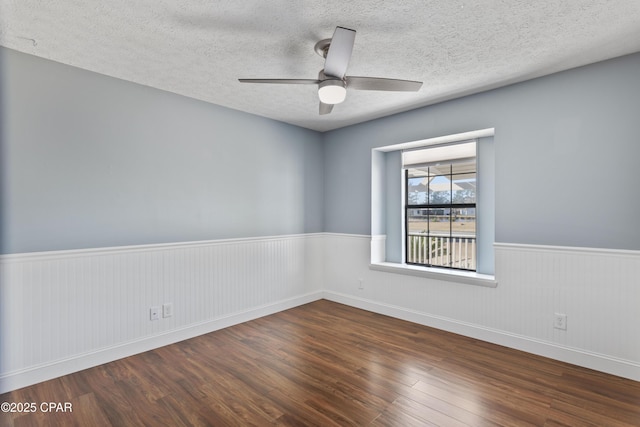 unfurnished room with ceiling fan, dark wood-type flooring, and a textured ceiling