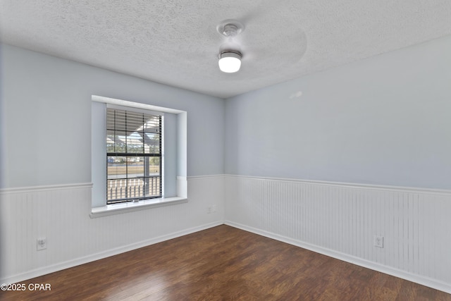 spare room with a textured ceiling and dark hardwood / wood-style floors