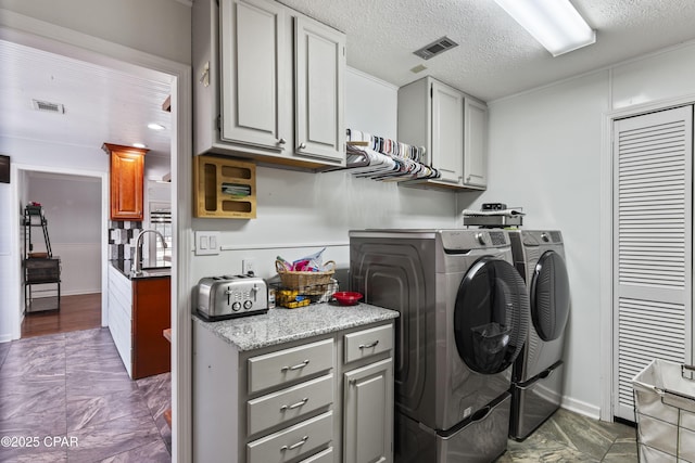 laundry room featuring cabinets, a textured ceiling, sink, and independent washer and dryer