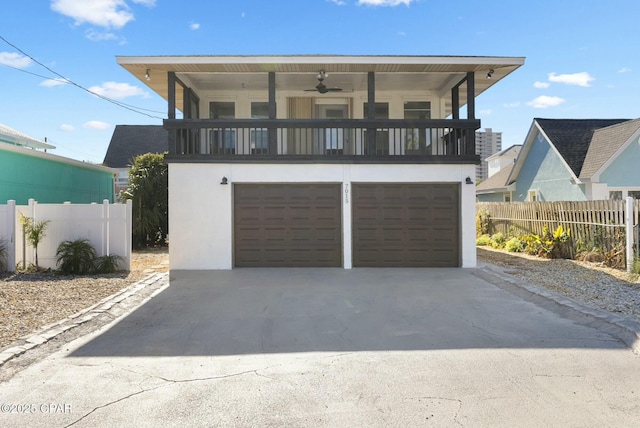 view of front of property featuring a balcony, a garage, fence, driveway, and stucco siding