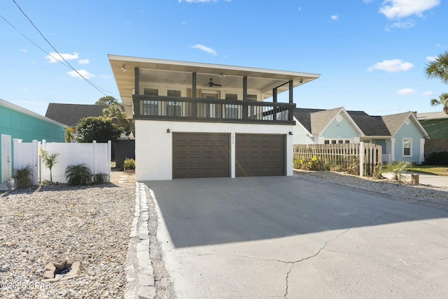 view of front of home featuring stucco siding, an attached garage, fence, a balcony, and driveway